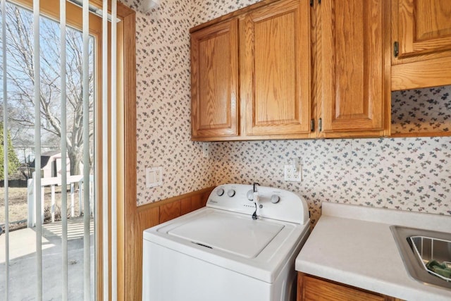 washroom with cabinet space, washer / dryer, wallpapered walls, and a sink