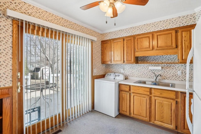 clothes washing area featuring ornamental molding, a sink, cabinet space, wallpapered walls, and washer / dryer