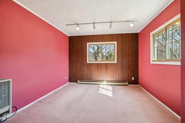 carpeted empty room with baseboards, heating unit, baseboard heating, and wood walls