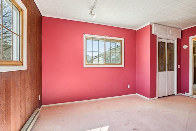 unfurnished room with baseboards, carpet floors, a baseboard radiator, ornamental molding, and rail lighting