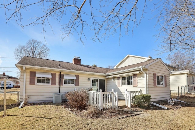 rear view of property with a yard, a chimney, roof with shingles, and fence