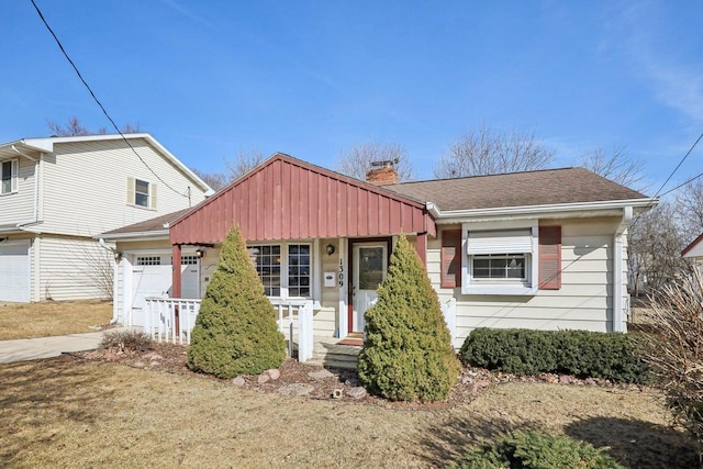 view of front of property featuring a shingled roof, a porch, driveway, and a chimney