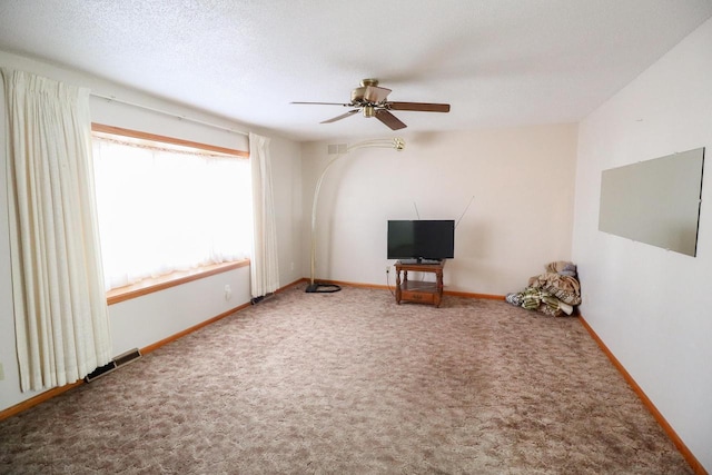 unfurnished living room with ceiling fan, carpet flooring, baseboards, and a textured ceiling