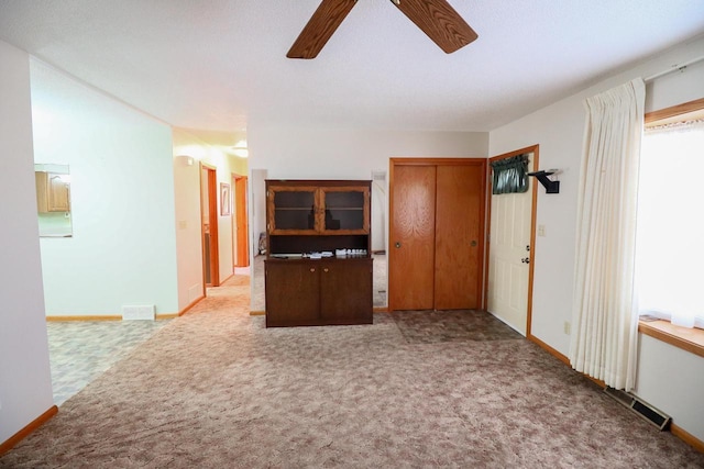 interior space featuring baseboards, carpet floors, and ceiling fan