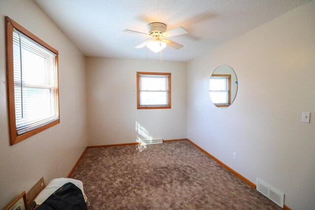 unfurnished room featuring baseboards, visible vents, carpet floors, and ceiling fan