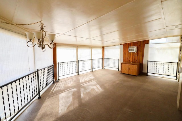 carpeted empty room featuring a notable chandelier, wood walls, and a wall mounted air conditioner