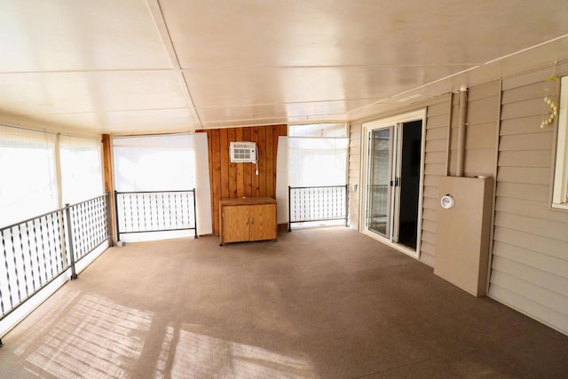 carpeted spare room featuring plenty of natural light, wooden walls, and a wall mounted AC