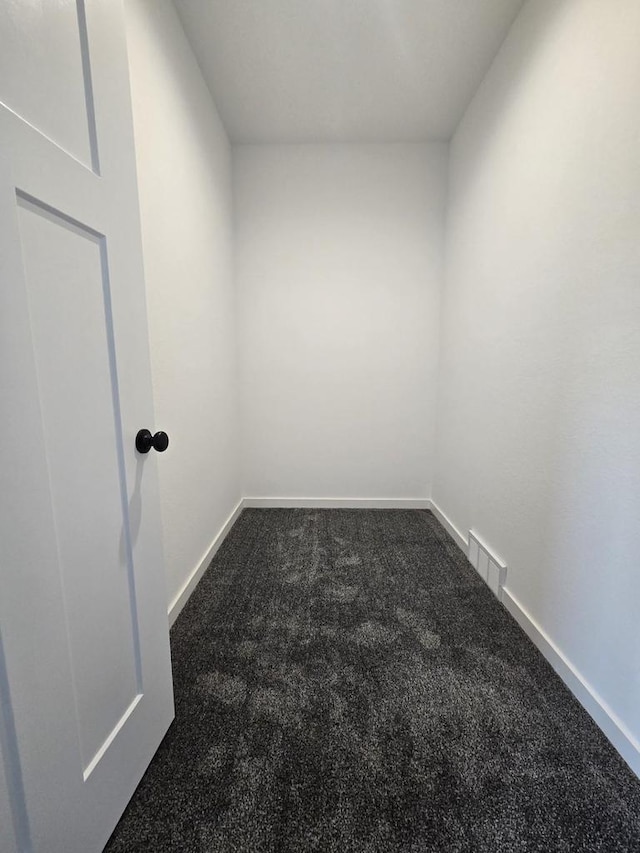 unfurnished room with dark colored carpet, visible vents, and baseboards