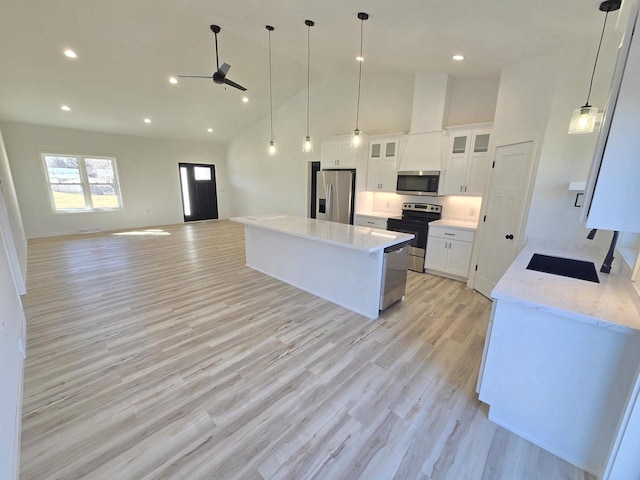 kitchen featuring high vaulted ceiling, a kitchen island, stainless steel appliances, white cabinetry, and light wood-type flooring