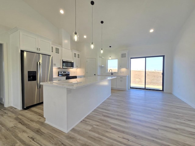 kitchen featuring a kitchen island, light countertops, white cabinets, stainless steel appliances, and a sink