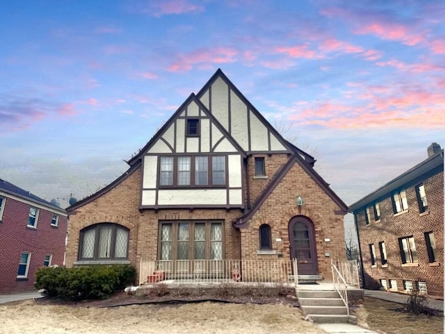 tudor home featuring stucco siding, brick siding, and french doors