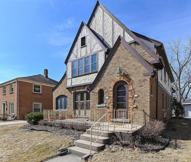 tudor home featuring brick siding and covered porch