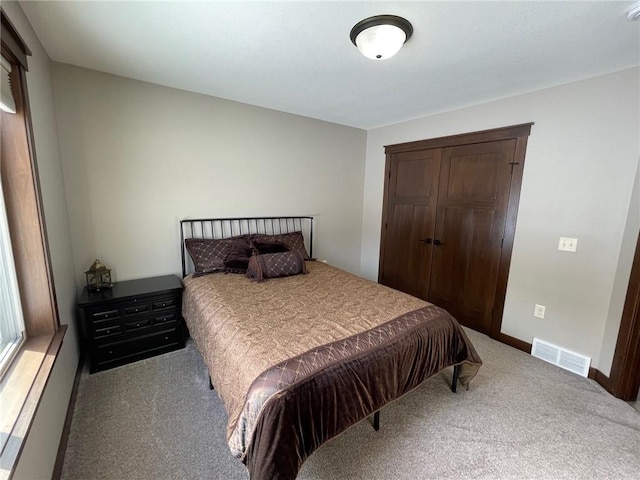 bedroom featuring carpet flooring, baseboards, visible vents, and a closet