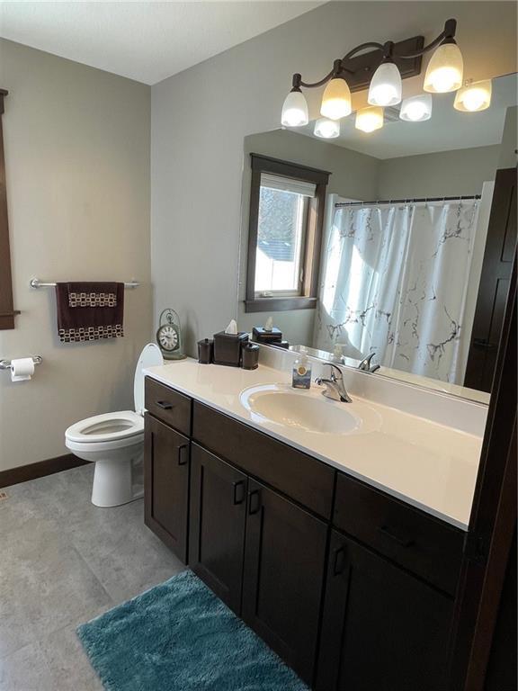 full bath featuring a shower with shower curtain, toilet, vanity, and baseboards