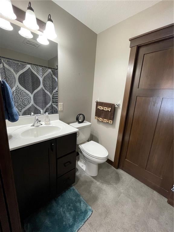 bathroom with toilet, vanity, and a shower with shower curtain