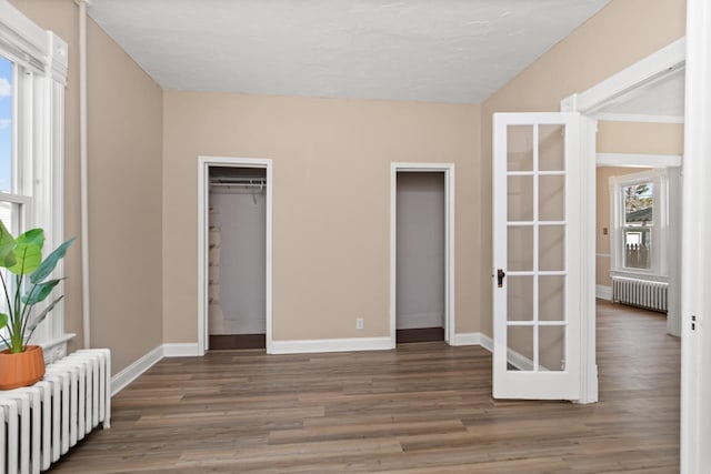 unfurnished bedroom featuring radiator heating unit, wood finished floors, and baseboards