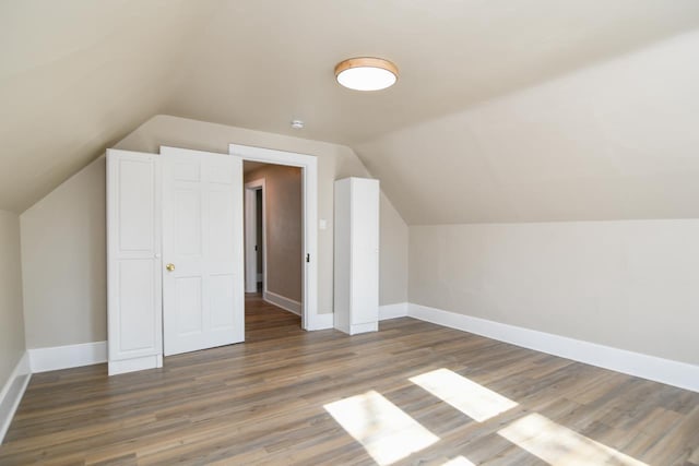 bonus room with baseboards, lofted ceiling, and wood finished floors