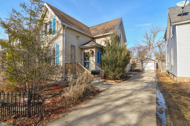 view of side of property featuring a garage, concrete driveway, an outdoor structure, and fence