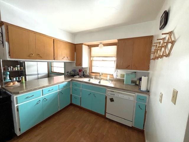 kitchen with dark wood finished floors, light countertops, white dishwasher, and a sink