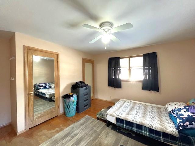 bedroom with baseboards, a ceiling fan, and wood finished floors