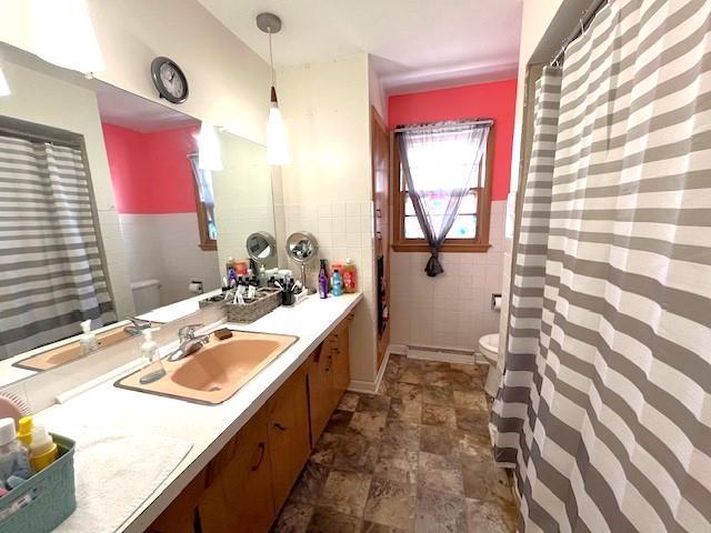 full bathroom with vanity, tile walls, toilet, and wainscoting