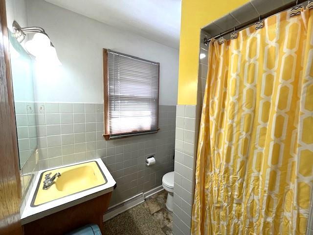 full bathroom featuring curtained shower, tile walls, toilet, wainscoting, and vanity