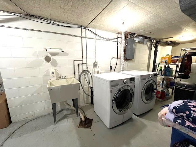 laundry area featuring laundry area, concrete block wall, electric panel, and washer and clothes dryer