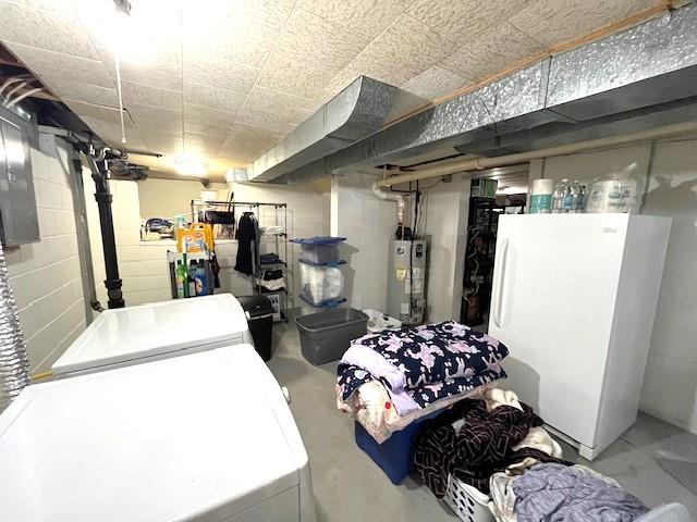 unfinished basement featuring washer / dryer, concrete block wall, water heater, and freestanding refrigerator