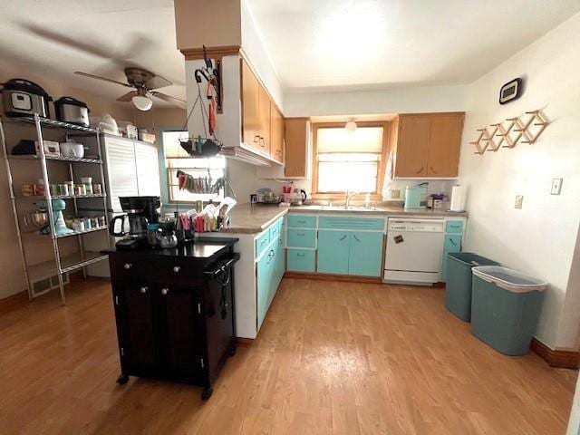 kitchen with a sink, light wood-style flooring, white dishwasher, and light countertops