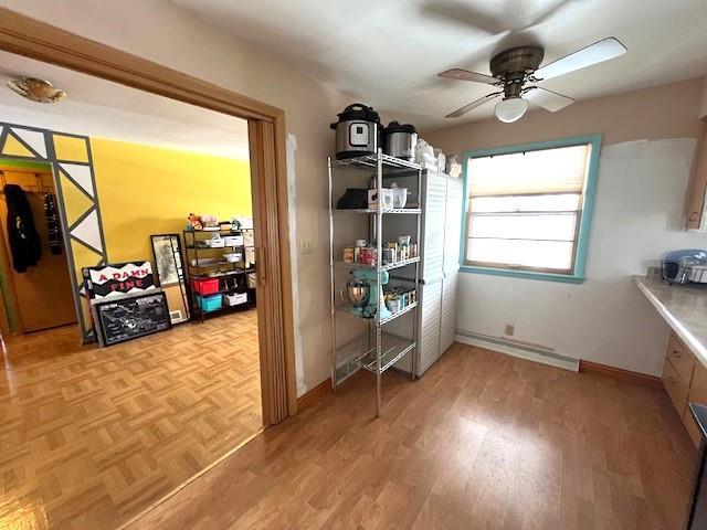 interior space with parquet flooring, baseboards, a baseboard heating unit, and ceiling fan