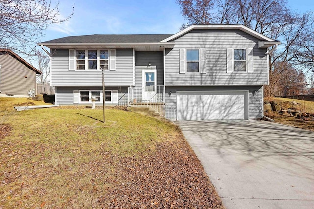 raised ranch featuring a front yard, a garage, and driveway