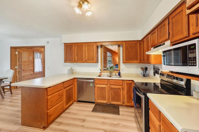 kitchen featuring a sink, under cabinet range hood, stainless steel appliances, light wood-style floors, and a peninsula