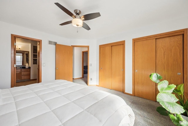 bedroom with baseboards, visible vents, ceiling fan, light carpet, and two closets