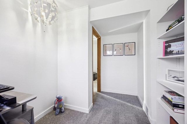 hall with a notable chandelier, baseboards, carpet, and visible vents