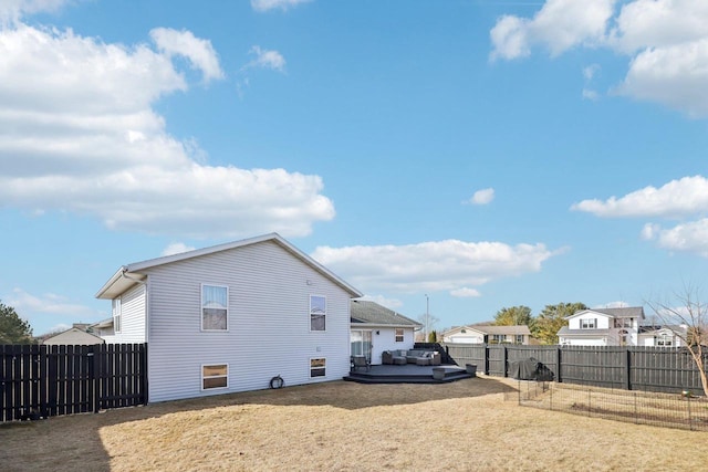 view of side of home with a lawn, a wooden deck, and a fenced backyard