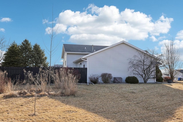 view of side of home featuring a lawn and fence