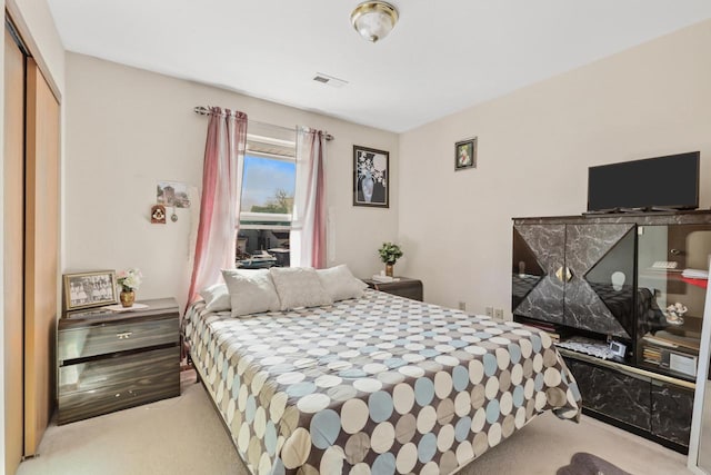 carpeted bedroom with visible vents and a closet