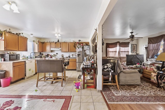 kitchen with under cabinet range hood, brown cabinets, stainless steel appliances, and light tile patterned flooring