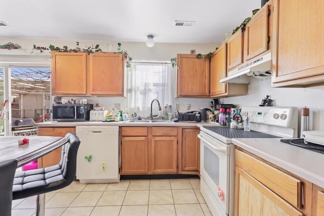 kitchen featuring visible vents, under cabinet range hood, a sink, white appliances, and light countertops