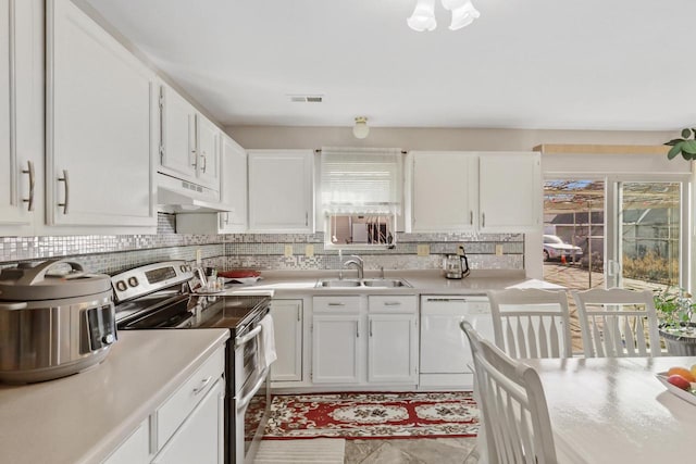 kitchen with under cabinet range hood, double oven range, white dishwasher, white cabinetry, and a sink