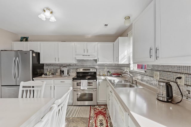 kitchen with under cabinet range hood, appliances with stainless steel finishes, light countertops, and a sink