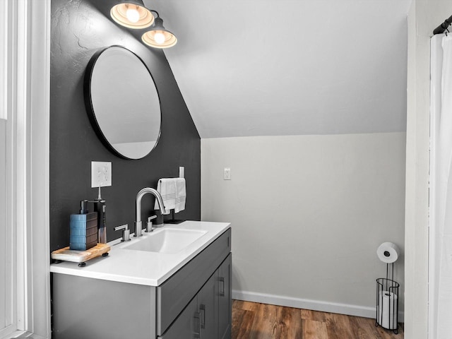 bathroom featuring vanity, vaulted ceiling, wood finished floors, and baseboards