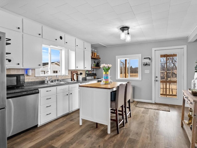 kitchen featuring butcher block countertops, open shelves, white cabinetry, black microwave, and dishwasher