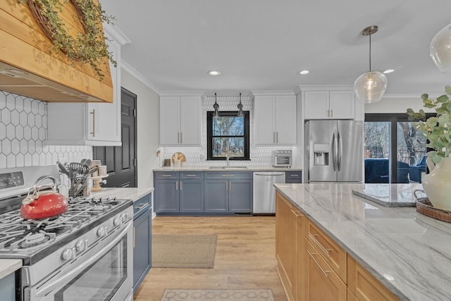 kitchen with light stone counters, premium range hood, a sink, stainless steel appliances, and crown molding