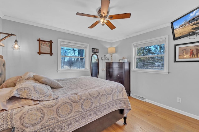 bedroom with baseboards, visible vents, ceiling fan, light wood-style floors, and crown molding