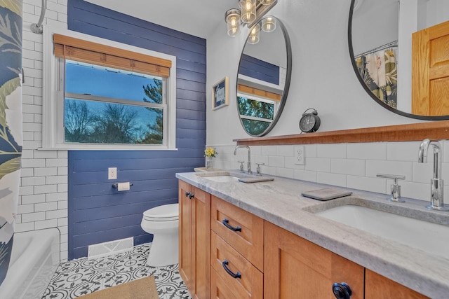 full bath with visible vents, wood walls, toilet, and a sink