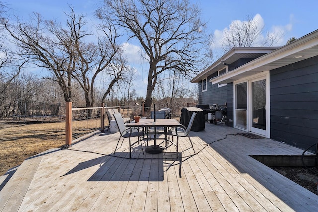 wooden deck with outdoor dining area and a trampoline