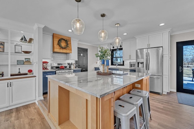 kitchen with a kitchen island, crown molding, light wood-type flooring, light stone counters, and appliances with stainless steel finishes