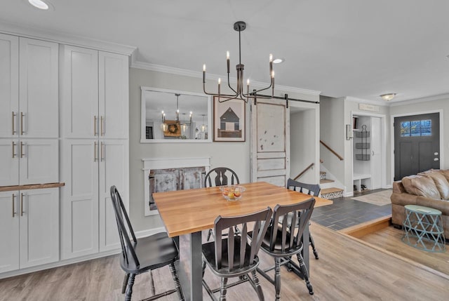 dining room with a barn door, stairway, light wood-style floors, and ornamental molding