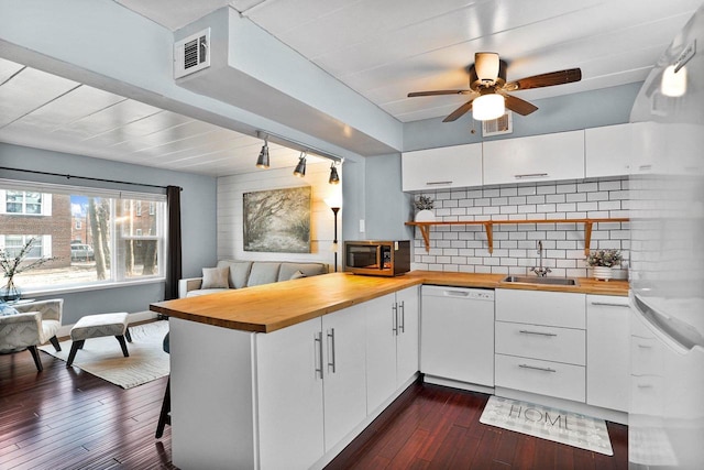 kitchen featuring wooden counters, a peninsula, a sink, dishwasher, and stainless steel microwave